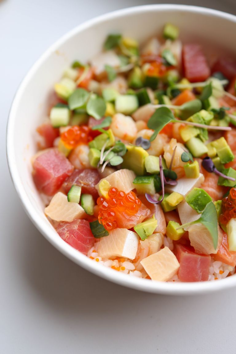 A colorful poke bowl with fresh fish, avocado, and microgreens in an appetizing presentation.