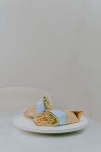 A fresh and tasty chicken wrap elegantly presented on a white plate with neutral background.