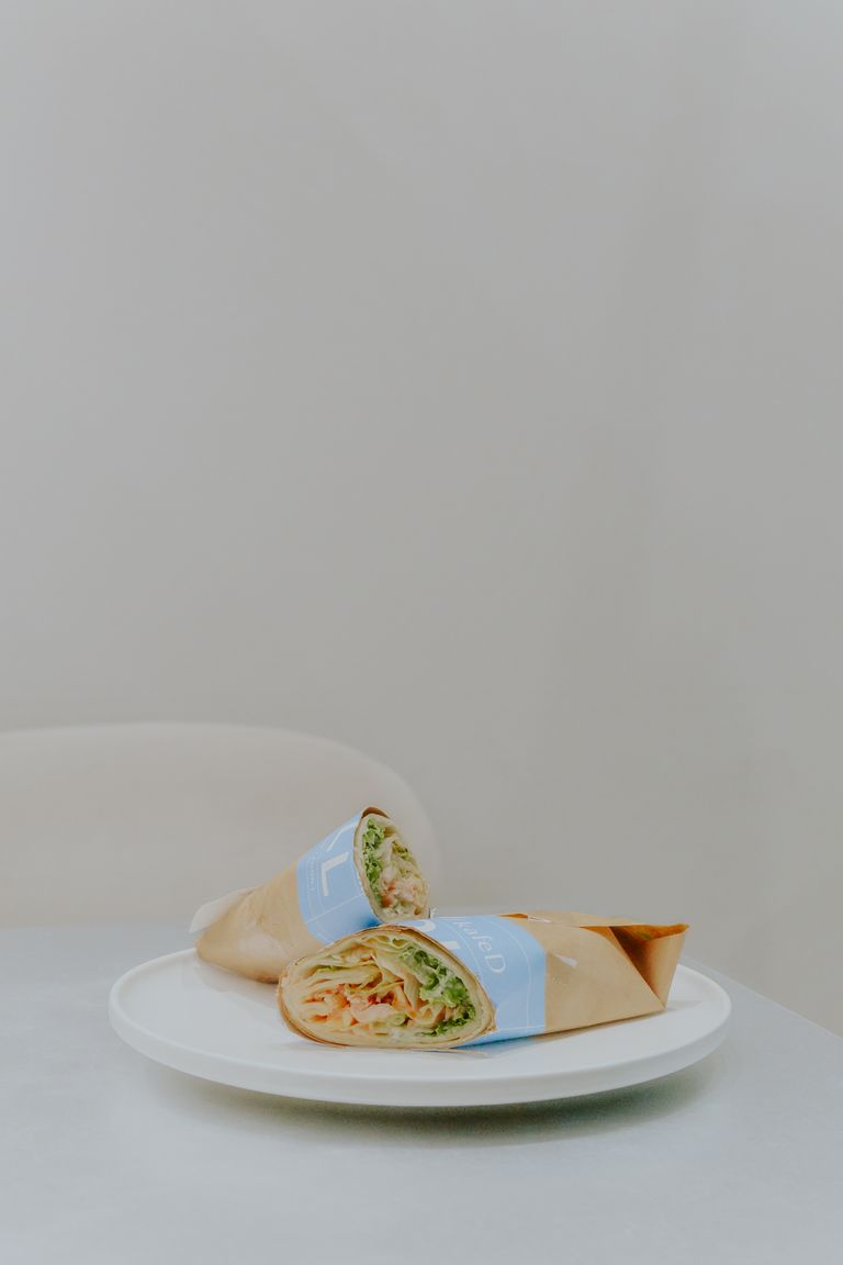 A fresh and tasty chicken wrap elegantly presented on a white plate with neutral background.