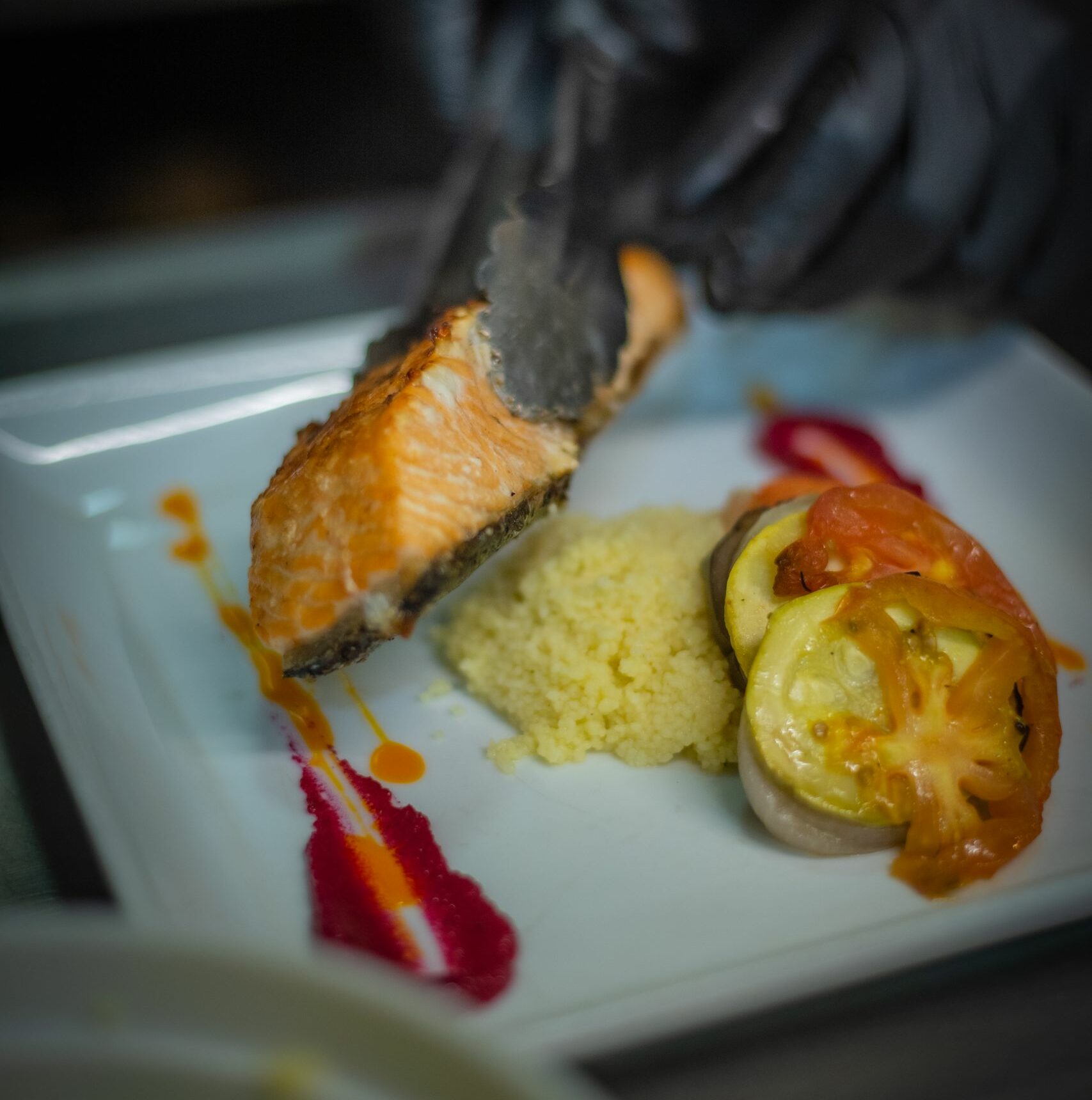 A gourmet salmon dish served with couscous and roasted vegetables artfully plated.