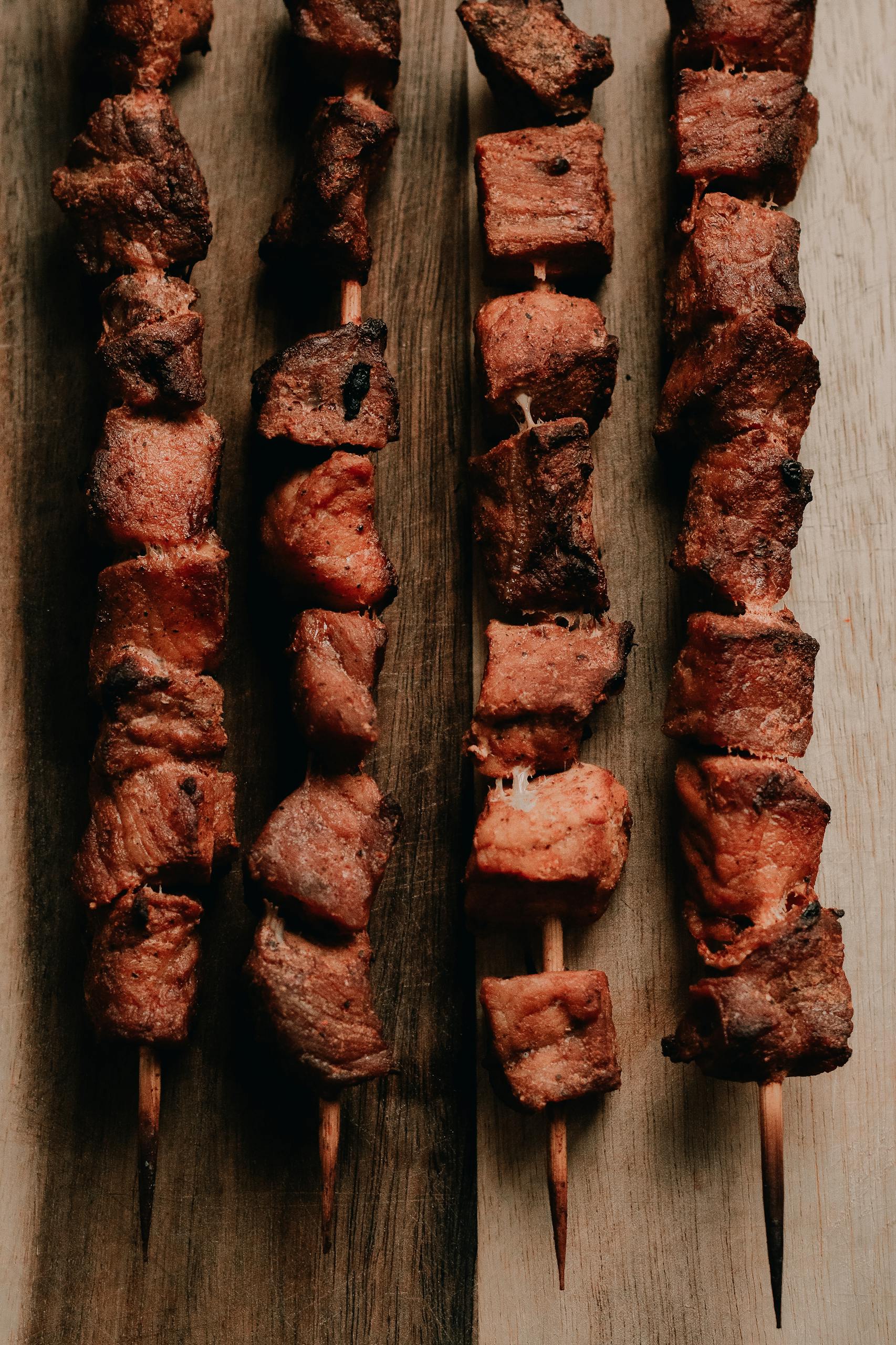 Appetizing grilled beef skewers arranged on a rustic wooden board, perfect for a BBQ theme.