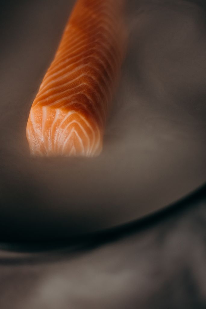 Close-up of a fresh salmon fillet enveloped in steam, perfect for food preparation imagery.