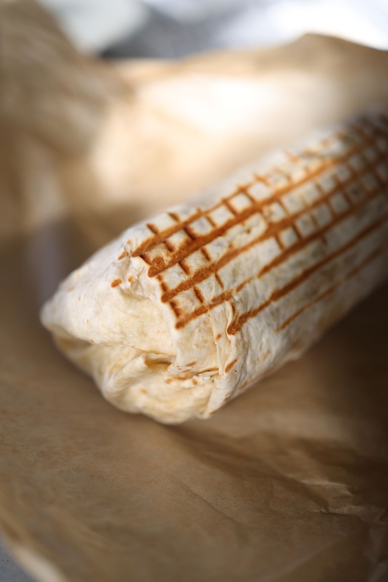 Close-up of a freshly grilled wrap with toasted marks, placed on brown paper for a rustic look.