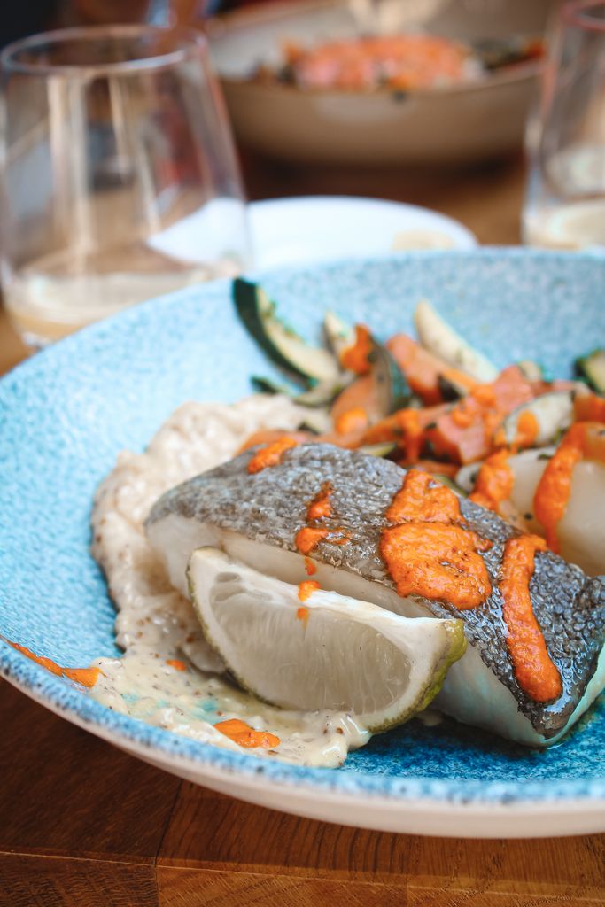 Close-up of a gourmet fish dish with lime and vegetables, showcasing fresh ingredients at a Lyon restaurant.
