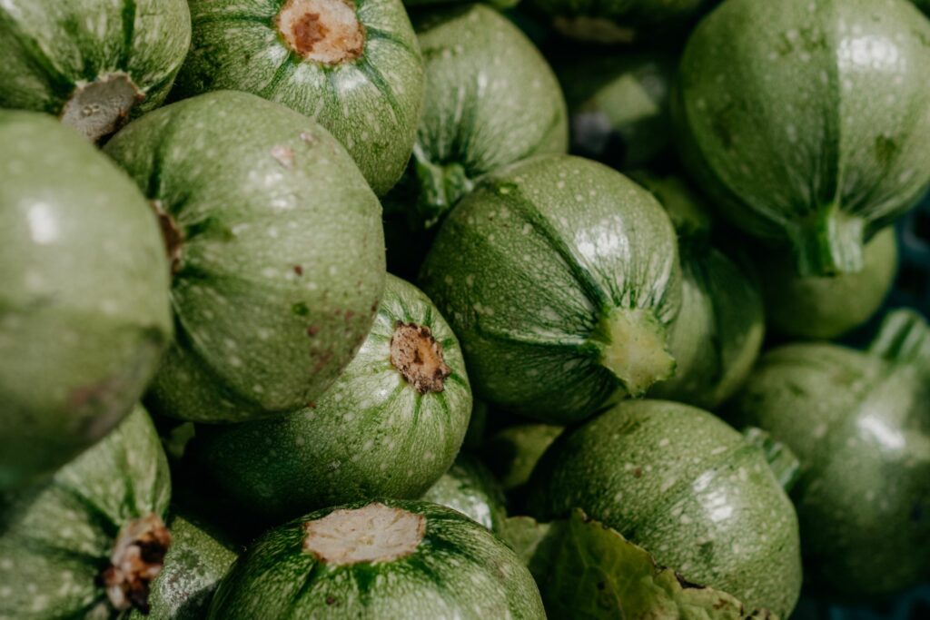 Close-up of green round zucchinis at a market, showcasing their fresh texture and vibrant color.
