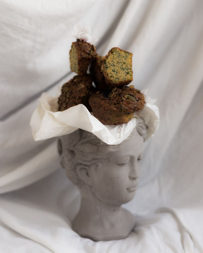 Creative display of rustic muffins on a classical sculpture, styled with elegance.