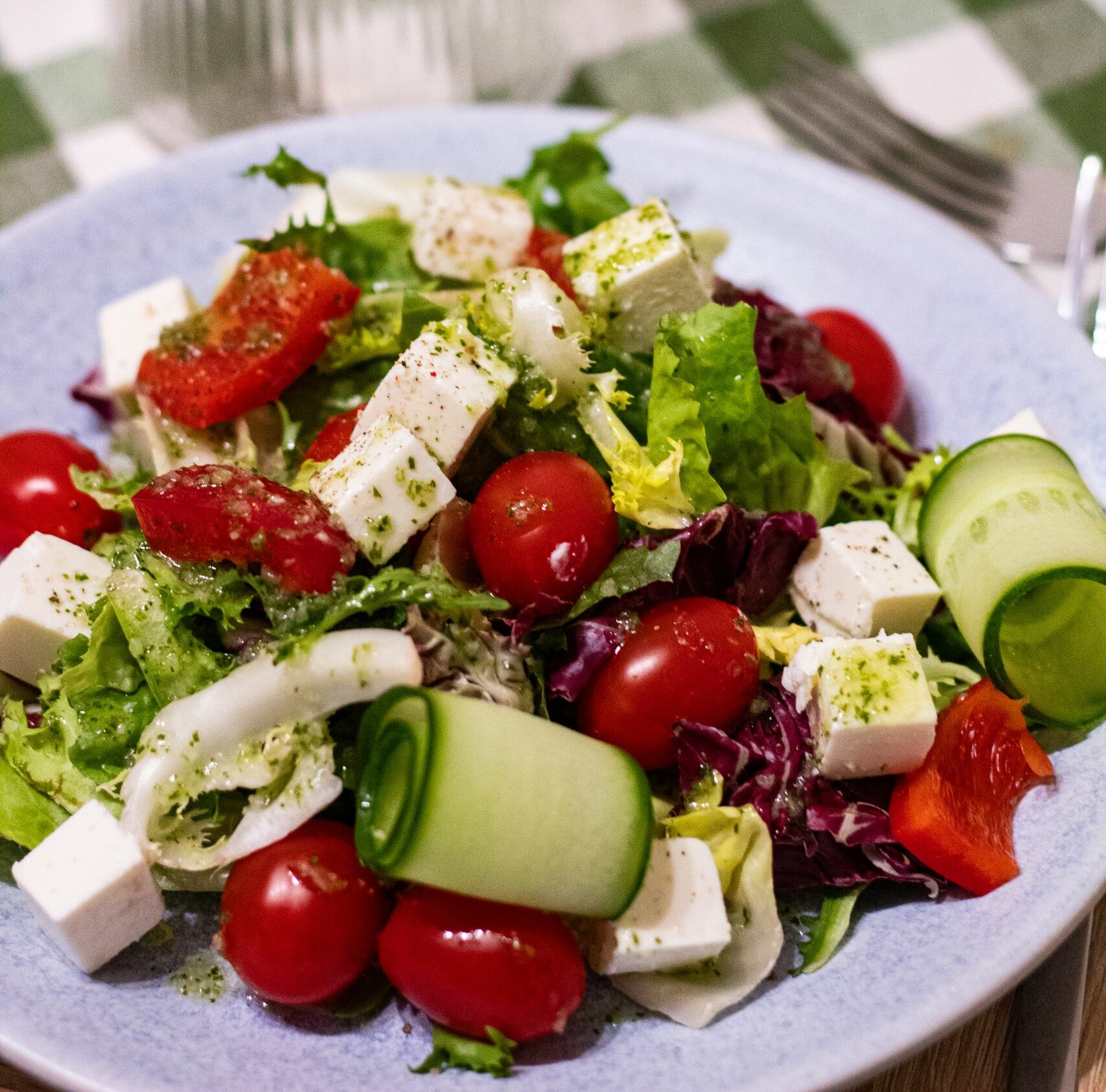 Delicious Greek salad featuring feta cheese, cherry tomatoes, cucumbers, and mixed greens.