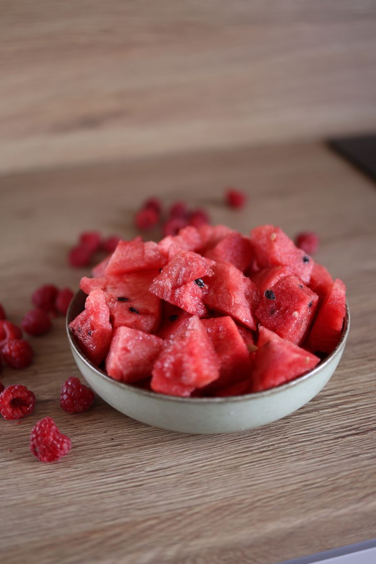Delicious watermelon chunks and fresh raspberries in a bowl, perfect for a healthy snack.