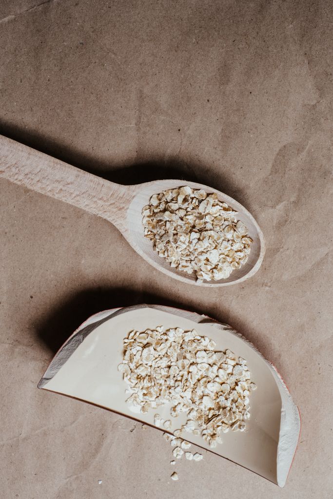 High-angle shot of oats in a broken ceramic bowl on a brown surface.