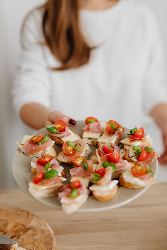 Plate of canapés with cured meats, cherry tomatoes, and herbs. Perfect for parties.