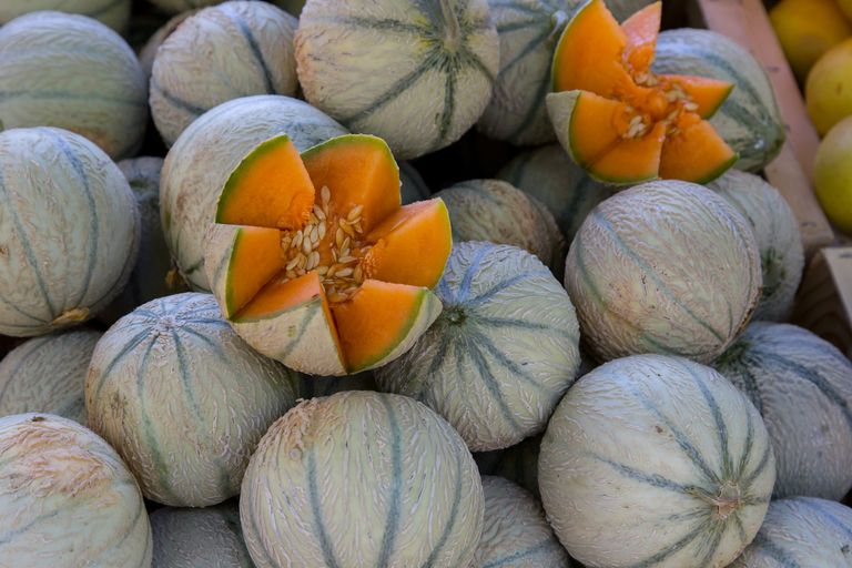 Ripe cantaloupes on display in a French market, showcasing their vibrant orange color.