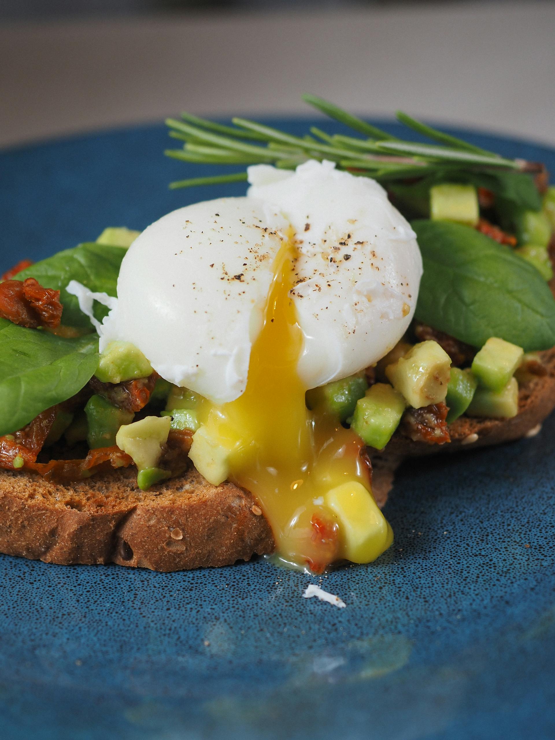 Savor the gourmet experience of poached egg and avocado toast on a rustic plate.