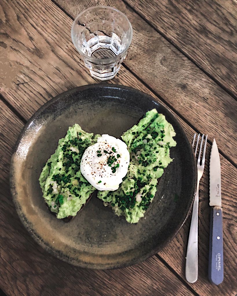 Savor the taste of avocado toast topped with a poached egg, served on a rustic plate for a perfect breakfast.