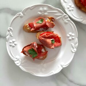 Tasty bruschetta with fresh tomato and herbs on an elegant white plate. Ideal for Italian cuisine enthusiasts.