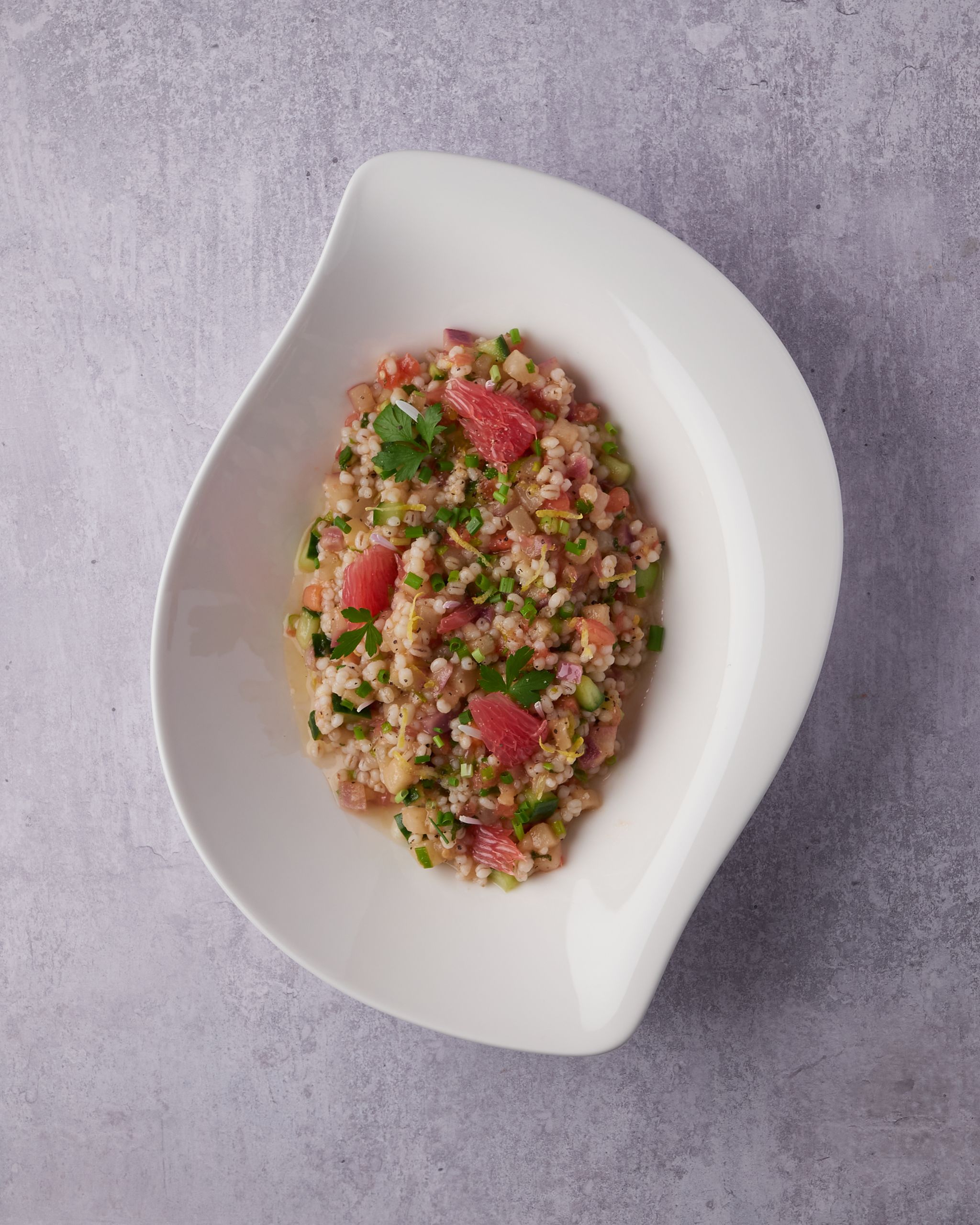 Top-down view of tuna porridge garnished with herbs in a ceramic dish on a gray surface.