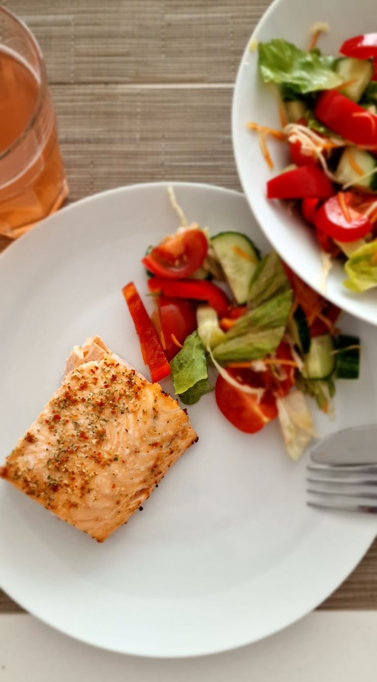 Top view of a healthy salmon fillet with a fresh vegetable salad, perfect for a nutritious meal.