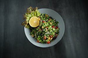 Top view of a vibrant Lebanese tabbouleh salad with fresh ingredients and a lemon garnish.