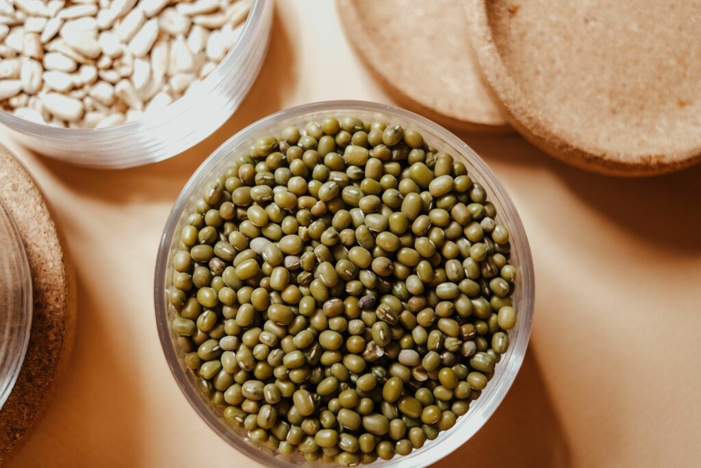 Top view of organic mung beans and seeds in glass jars, showcasing natural food storage.