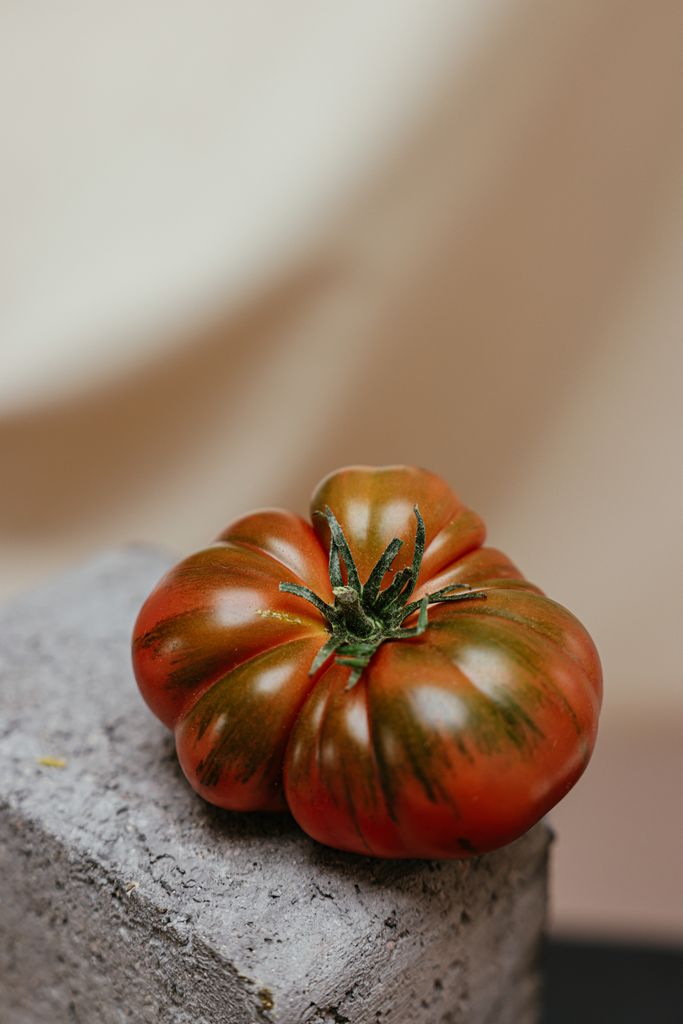 Vibrant, fresh heirloom tomato resting on a textured stone surface.