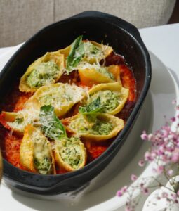A savory plate of stuffed pasta shells with spinach and cheese served alongside a glass of white wine.