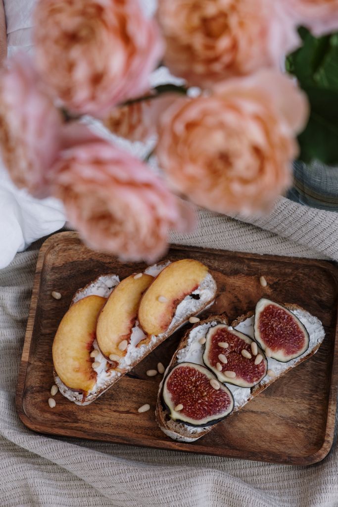 Artisan bread topped with fresh peach and fig slices arranged on a wooden board.