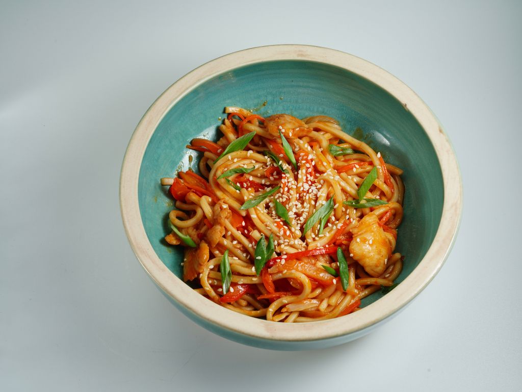 Close-up of a tasty chicken noodle dish garnished with sesame seeds.