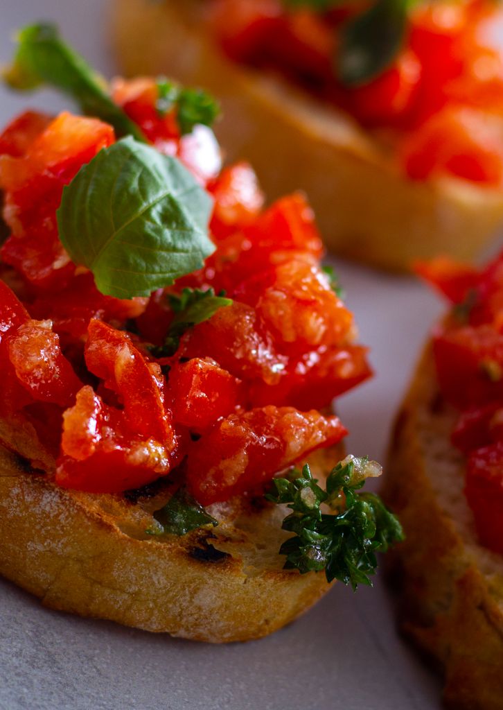 Delicious and fresh Italian bruschetta topped with diced tomatoes and basil leaves.