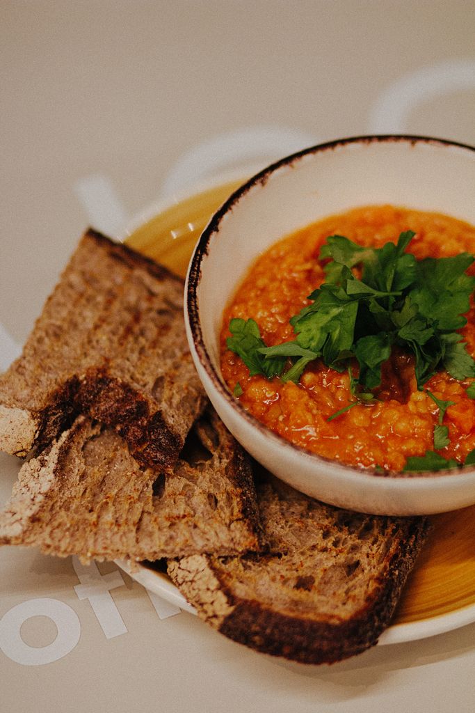 Delicious lentil soup garnished with fresh parsley, served with rustic bread slices.