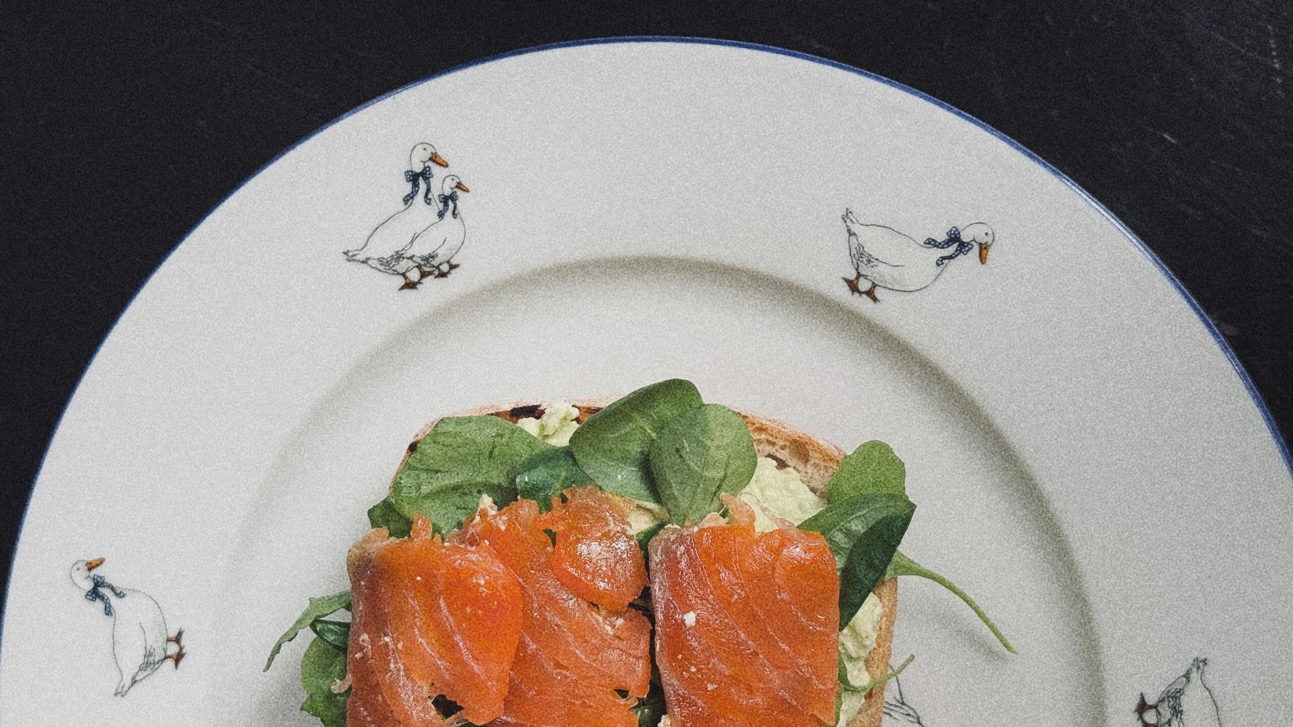 Delicious salmon and avocado toast served on a duck-themed plate.