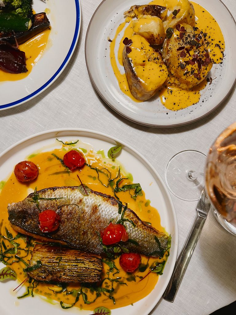 Elegant gourmet fish dinner plated with saffron sauce and roasted vegetables.