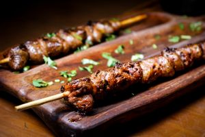 Juicy grilled meat skewers presented on a rustic wooden board.