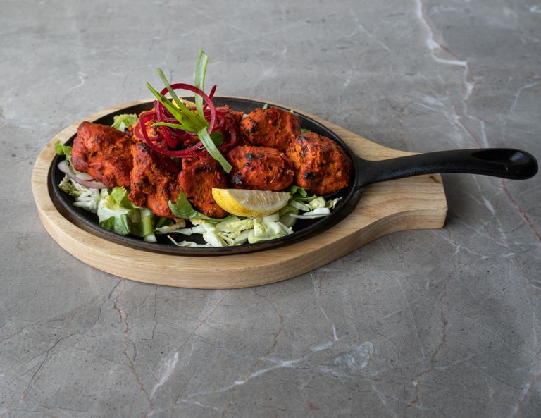 Mouthwatering tandoori chicken arranged on a sizzling platter, perfect for authentic Asian cuisine lovers.