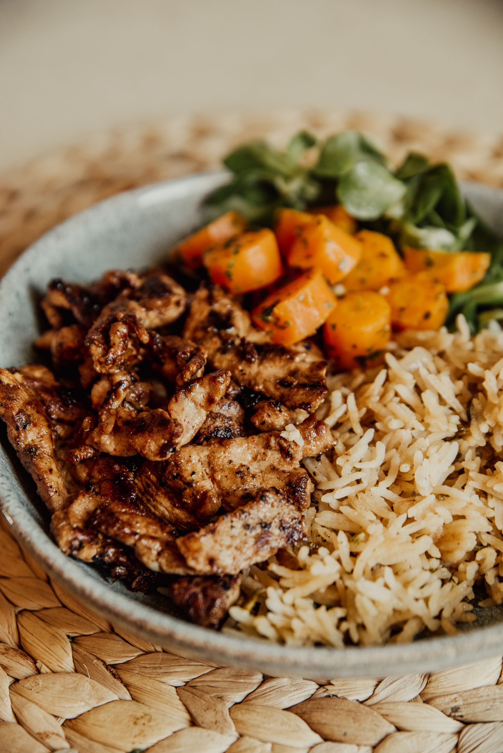 Tasty grilled chicken with rice and colorful vegetables served in a bowl, perfect for a healthy meal.