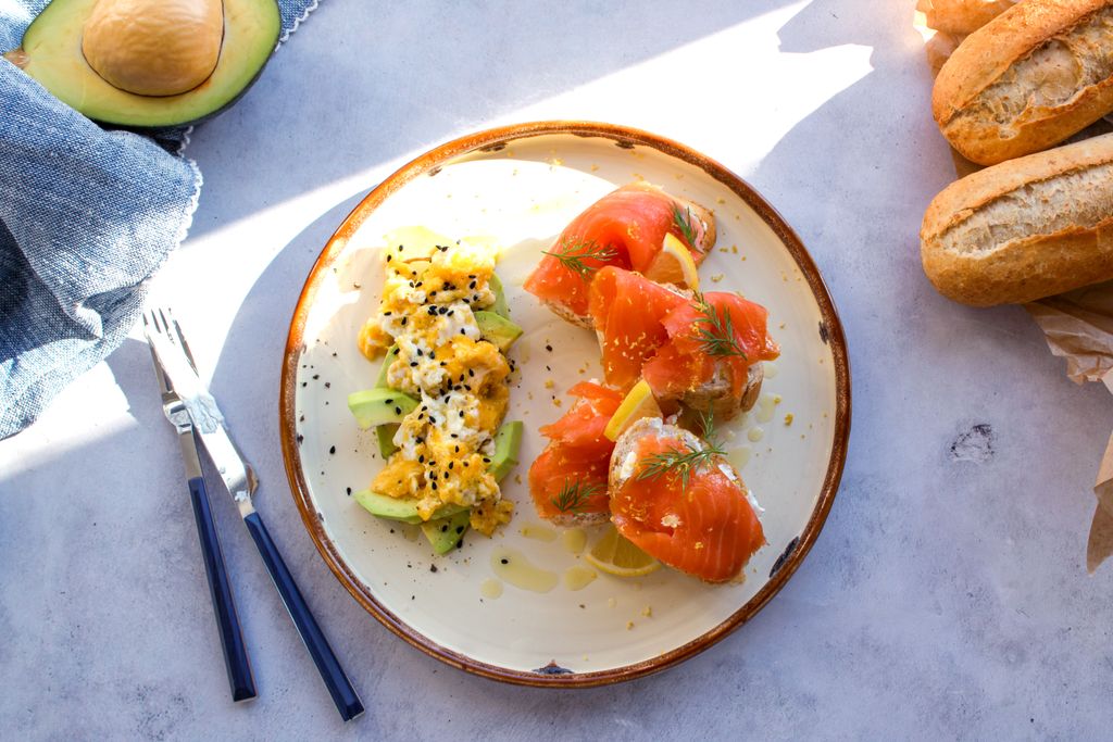 Top-down view of a breakfast platter with salmon, avocado, and baguettes, perfect for a fresh morning meal.