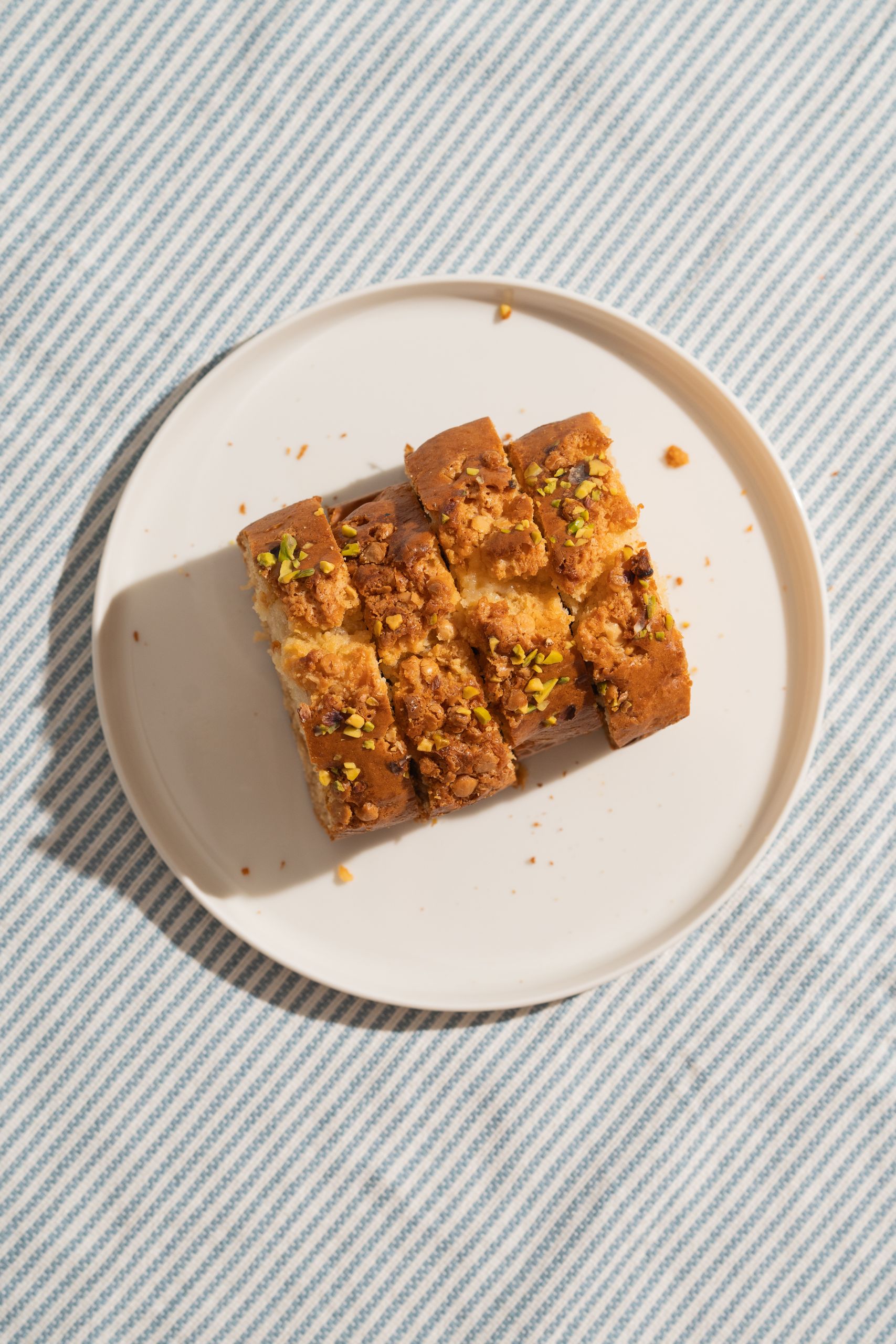 Top view of nut-topped cake slices on a plate with striped background, perfect for dessert themes.