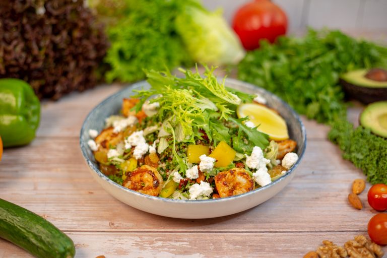 Vibrant quinoa salad topped with fresh vegetables, feta cheese, and lemon slice.