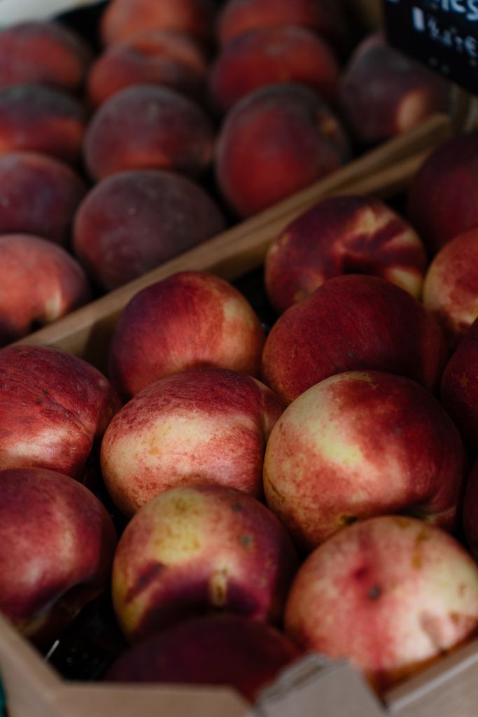 Vivid display of ripe peaches at a market stall, highlighting freshness and colors.
