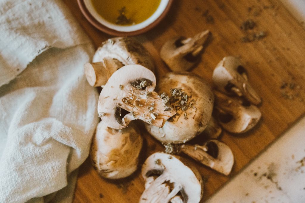 A closeup of fresh mushrooms on a wooden board ready for cooking, next to a cloth.
