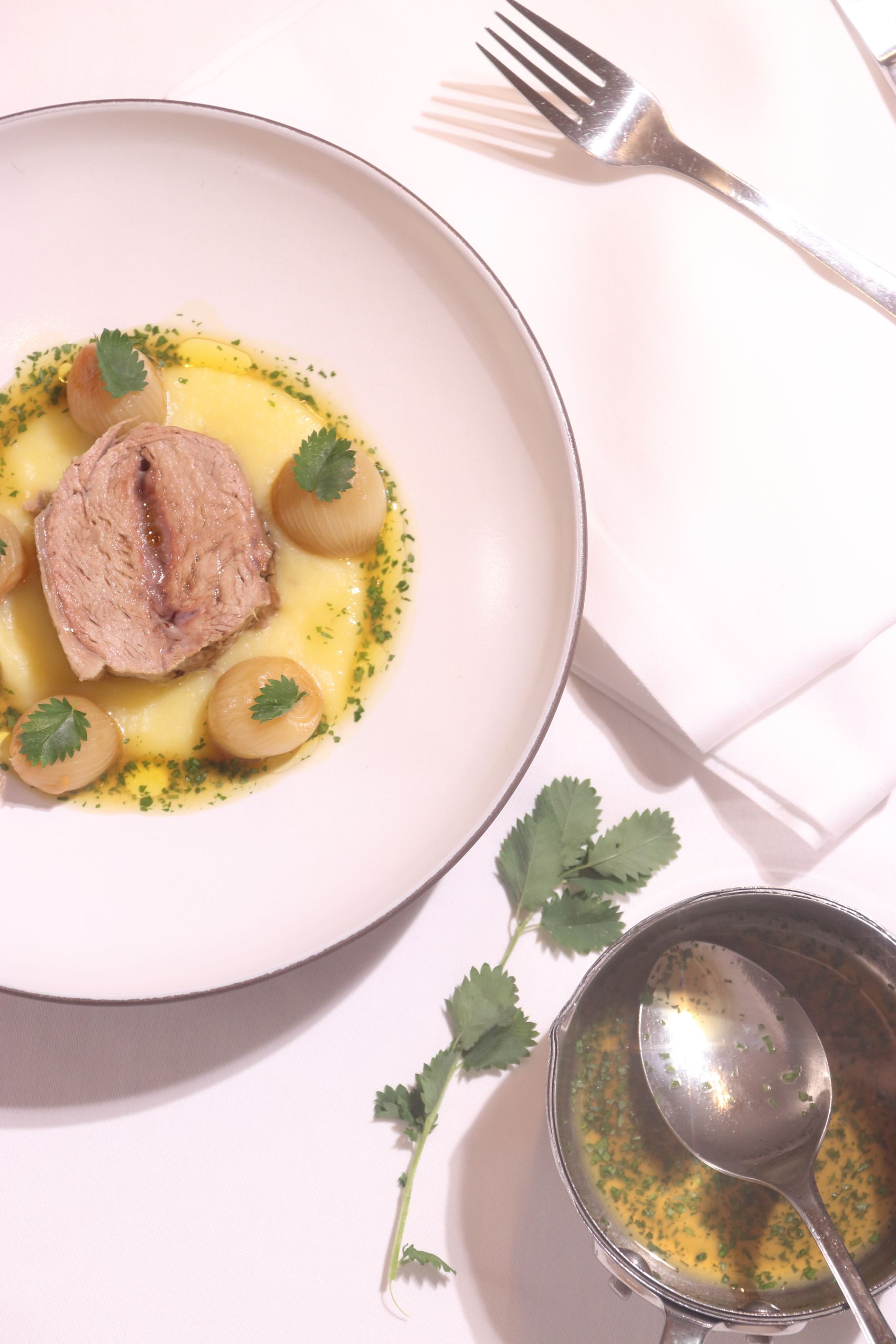 Artful pork dish garnished with greens, elegantly plated, captured in Trentino-Alto Adige, Italy.