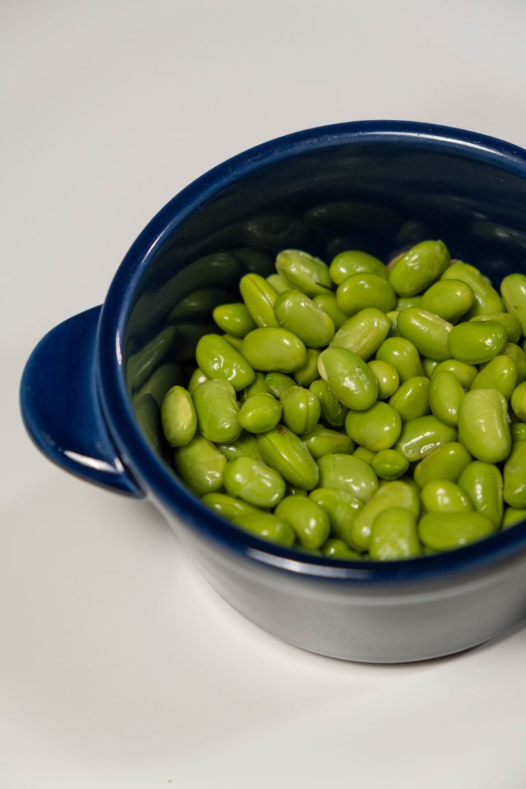Close-up of fresh green edamame beans in a vibrant blue bowl, perfect for healthy eating.