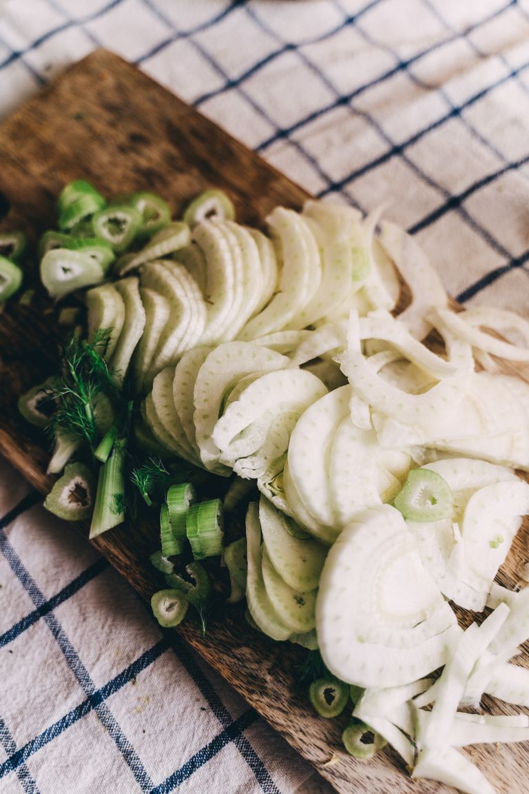 Close-up of fresh sliced fennel on a wooden chopping board, perfect for vegan cuisine.