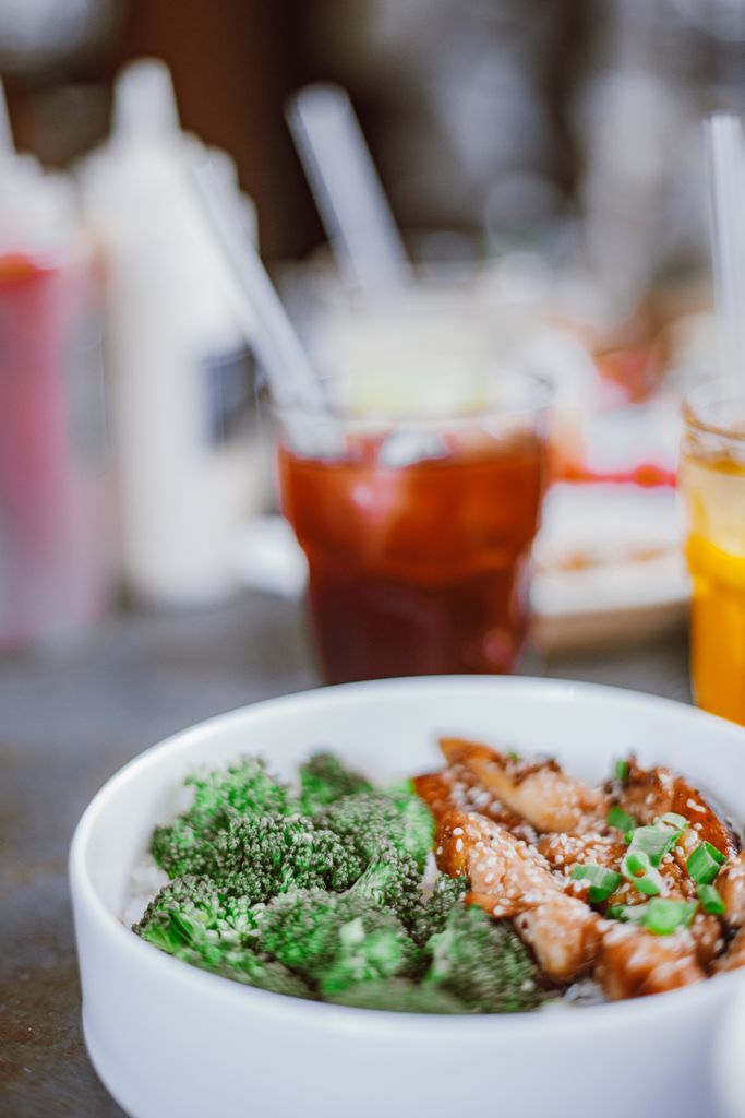Delicious broccoli and chicken dish served in a white bowl with drinks in the background.