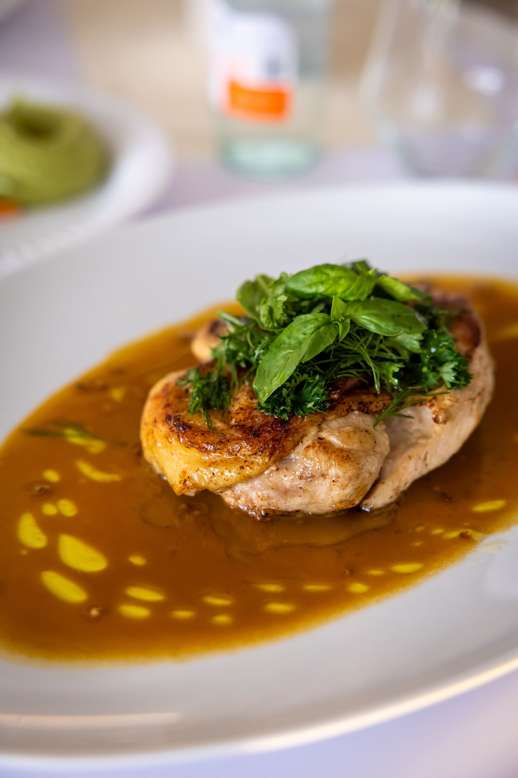 Delicious grilled chicken with fresh herbs in rich sauce on a white plate.