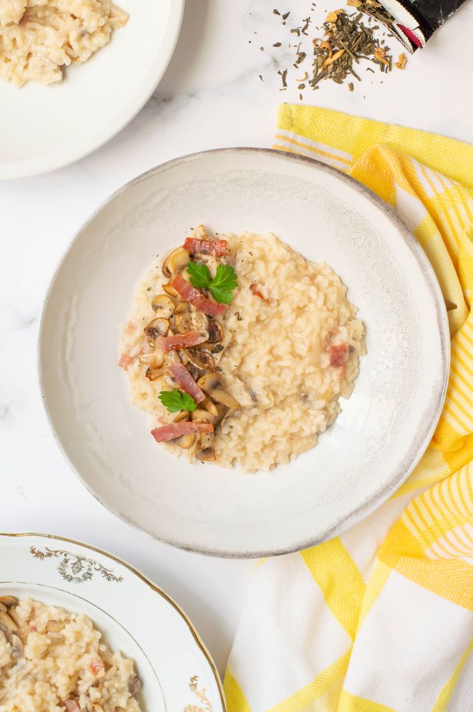 Elegant mushroom and ham risotto served on a white plate, topped with parsley.