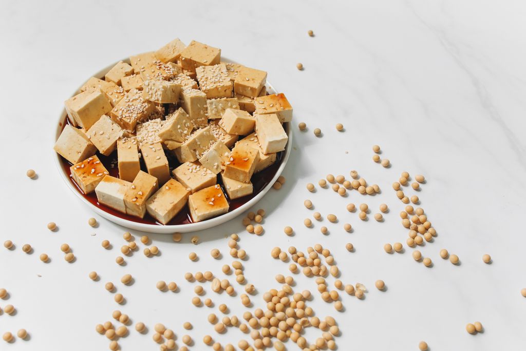 Flat lay of tofu cubes drizzled with soy sauce and sprinkled with sesame seeds.