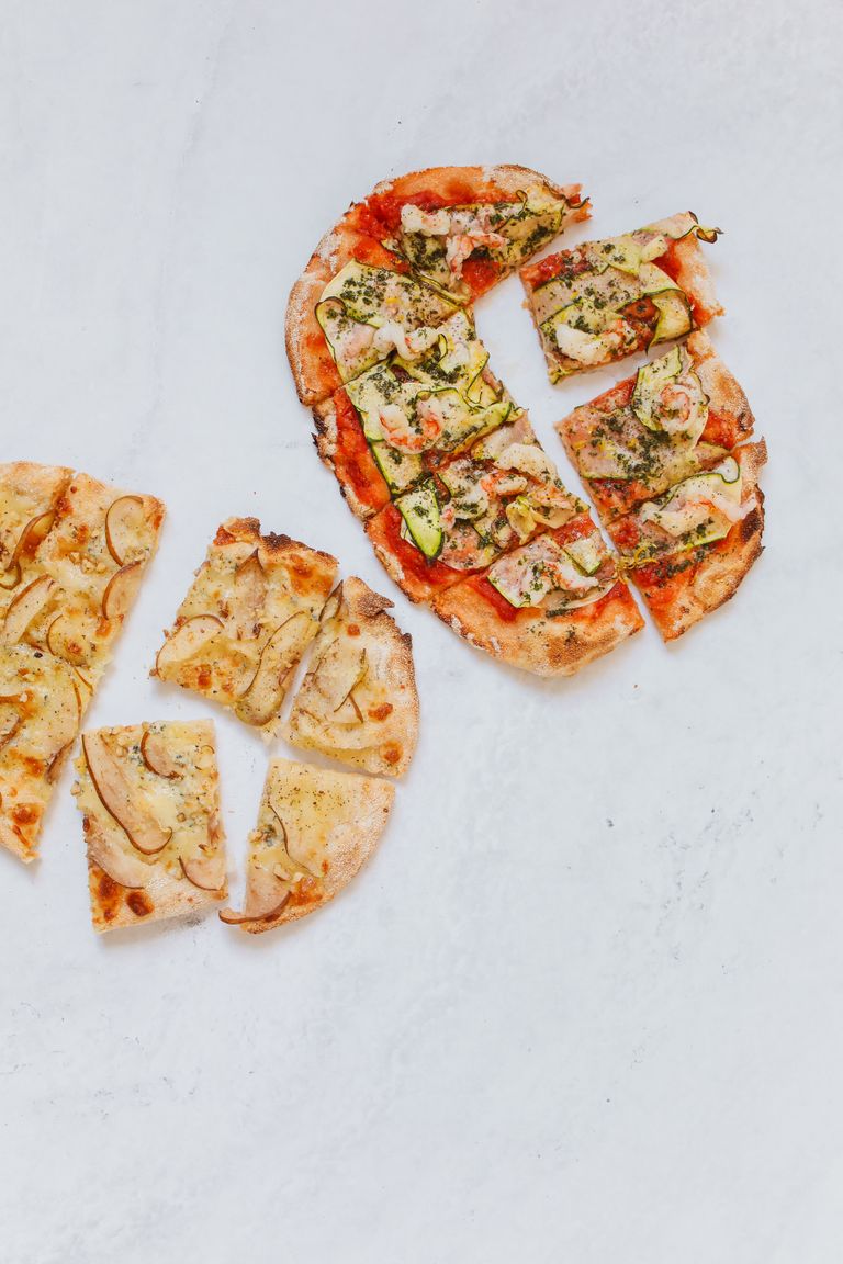 Overhead view of sliced Italian pizzas with diverse toppings on a white background.