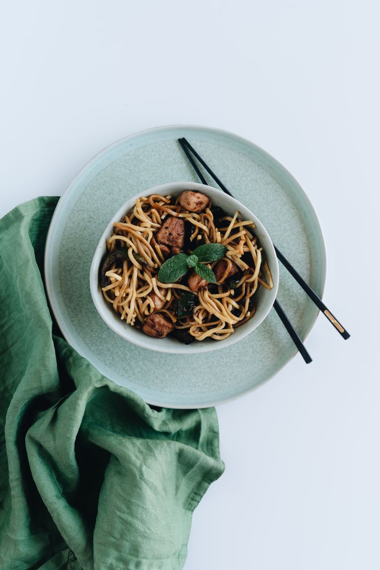 Savor a bowl of Asian noodles served with chopsticks on a stylish plate.