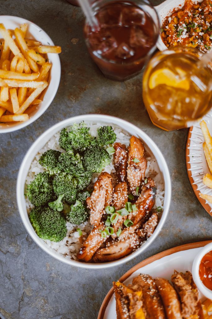 Savor the taste of Asian cuisine featuring chicken, broccoli, and rice with sides of fries. Perfect for dinner.