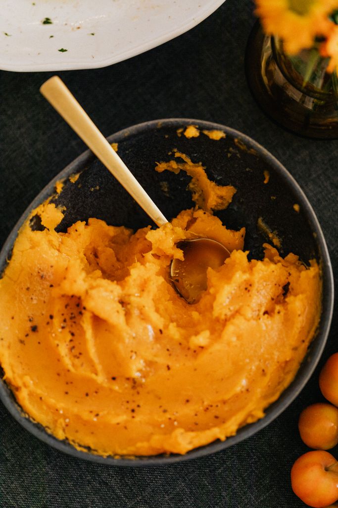 Top view of creamy pumpkin mashed potatoes in a bowl with spices.