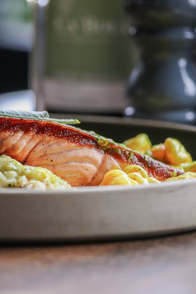 Delicious grilled salmon fillet served with mashed potatoes and vegetables on a plate.